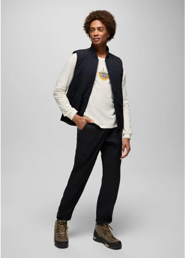 Person wearing a black vest over a white shirt with a graphic design, black pants, and brown boots on a light gray background.