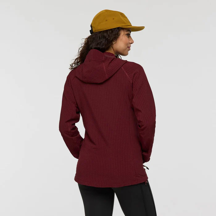 Person wearing a maroon jacket and mustard cap on a light gray background