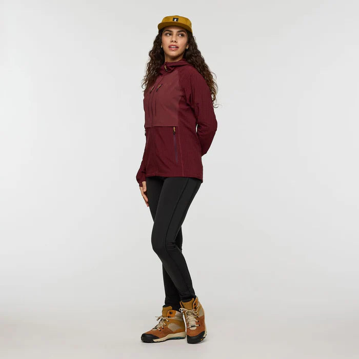 Woman wearing a maroon jacket, black leggings, and brown boots on a white background