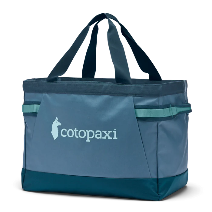 Blue tote bag with 'cotopaxi' logo on a white background
