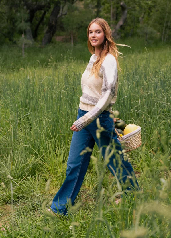 Woman walking through a field with a basket of fruits