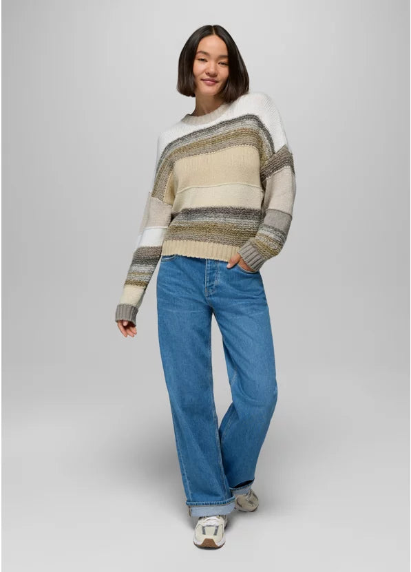 Person wearing a striped sweater and blue jeans on a plain background