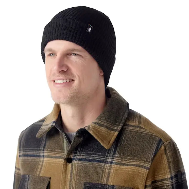 Man wearing a smartwool beanie in black and plaid shirt on a white background