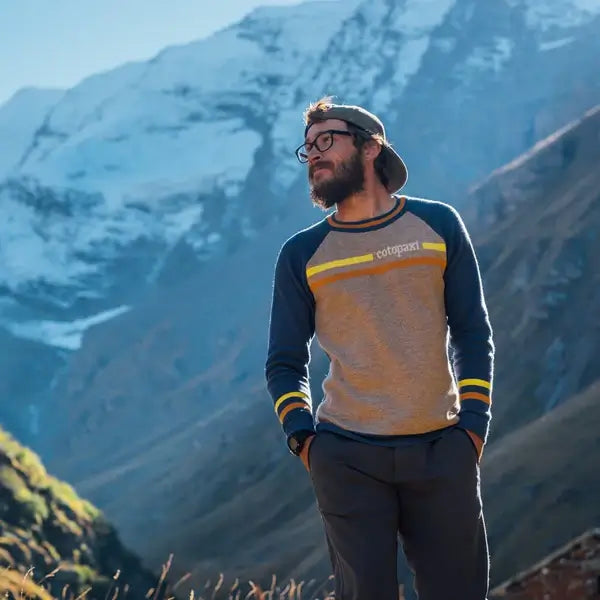 Guy in mountain landscape wearing a cotopaxi sweatshirt.