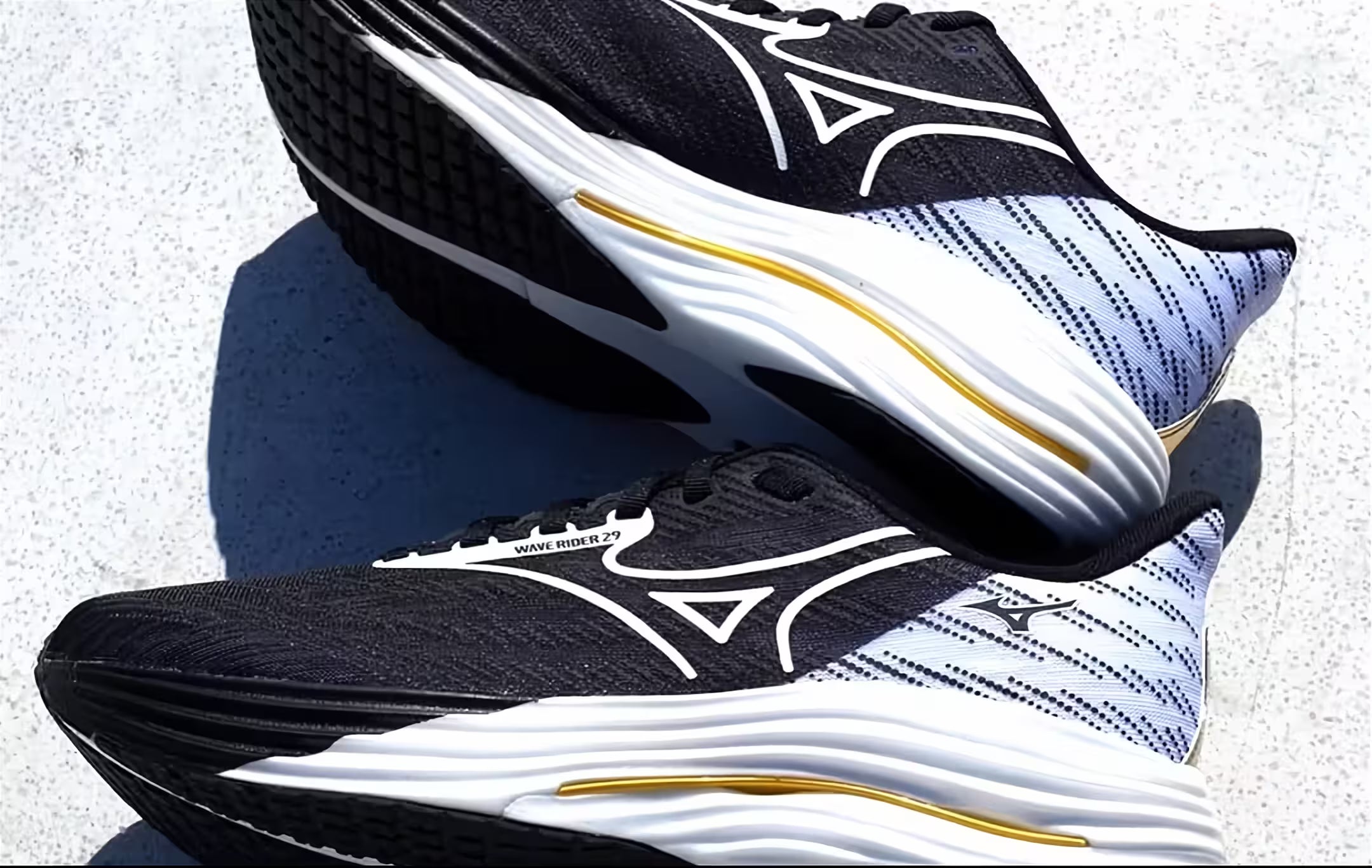 Pair of black and white running shoes with gold accents on a concrete surface