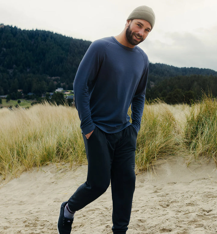 Man standing on a sandy path with grass and trees in the background