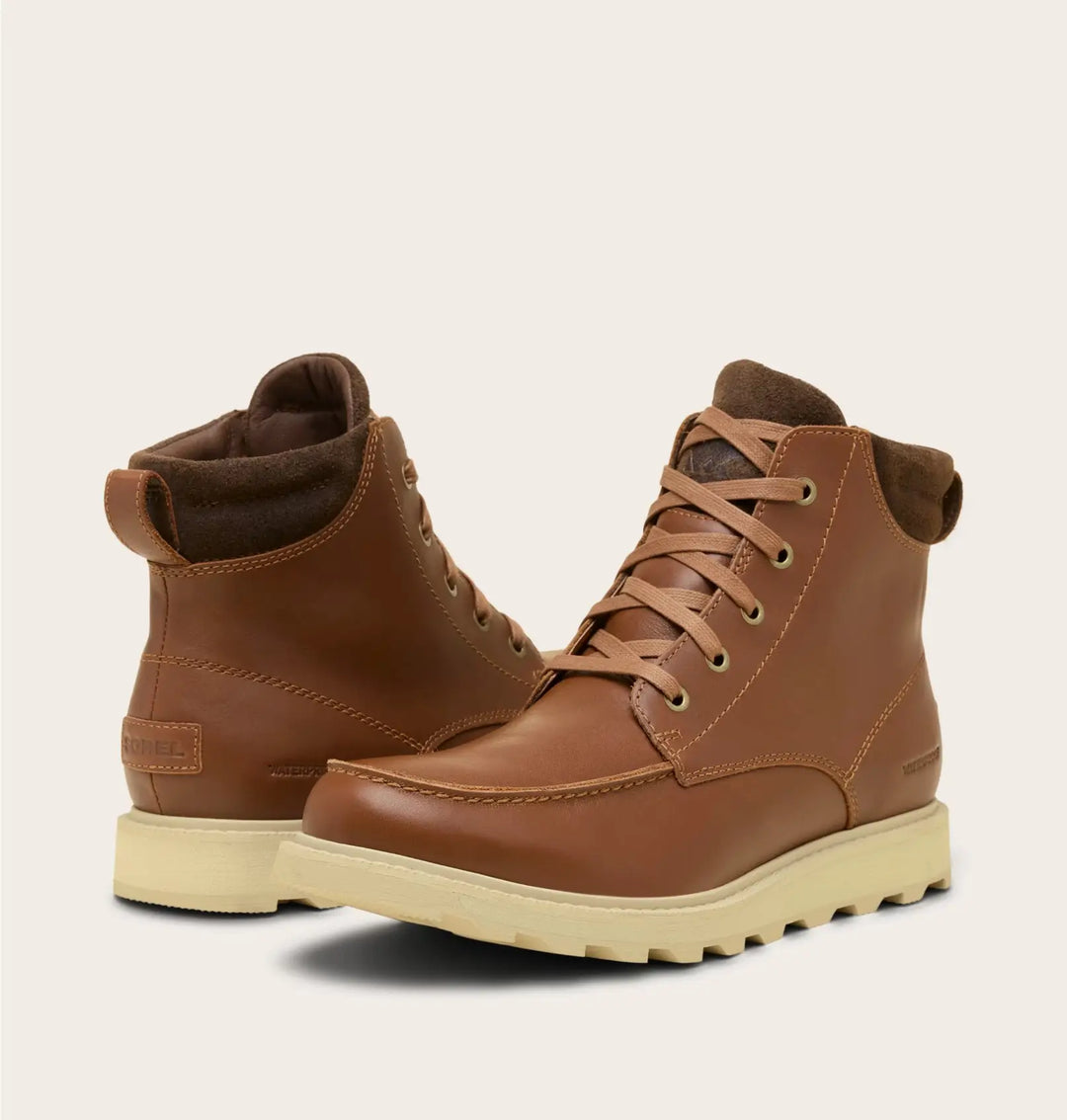 Pair of brown leather boots with beige soles on a light beige background