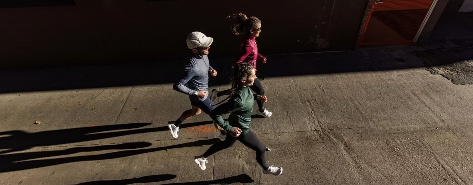 Three people running on a street with a building in the background - The Shoe Collective
